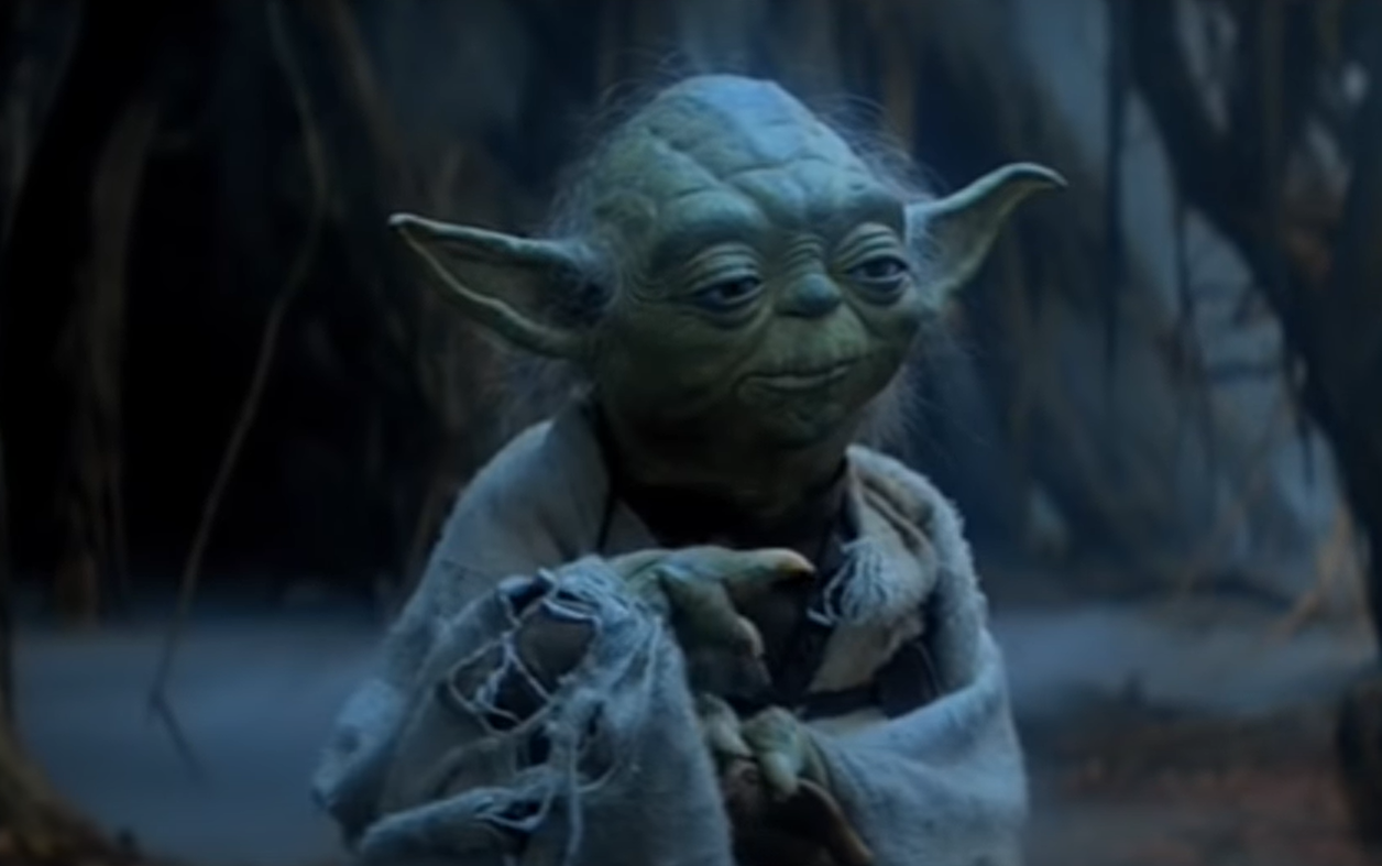 yoda character in torn robe standing in the midst of the forest